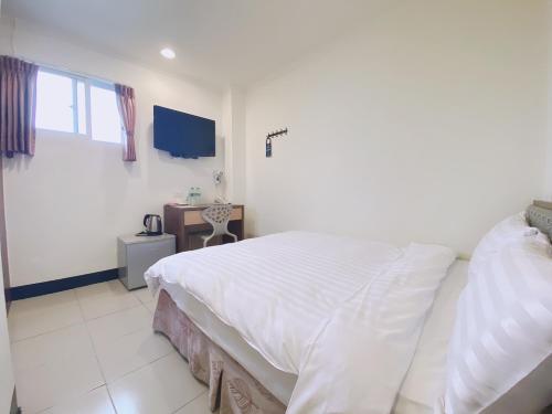 a bedroom with a large white bed and a window at Lai Chi Te Hotel in Tainan