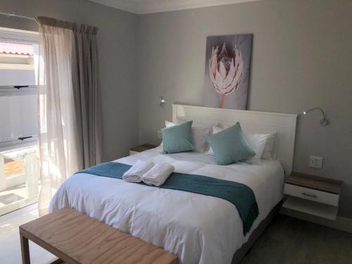 a bedroom with a large white bed with blue pillows at Hermanus Guest Rooms in Hermanus
