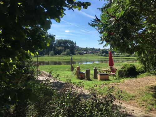 a park with chairs and a table and a red umbrella at Pension Elbkiosk in Kleinzadel