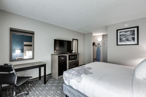 a hotel room with a bed and a desk and a television at Days Inn & Suites by Wyndham Spokane in Spokane