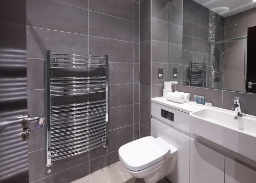 La salle de bains est pourvue de toilettes, d'un lavabo et d'un miroir. dans l'établissement Luxustay Clyde House, à Milton Keynes