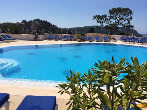 une grande piscine avec des chaises longues bleues dans l'établissement Appartement Ange Gardien Vue Mer, à Villefranche-sur-Mer