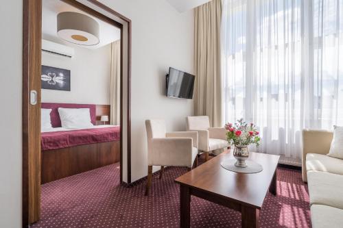 ブロドニツァにあるHotel Storkのベッド、テーブル、鏡が備わる客室です。