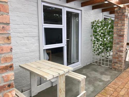 a wooden bench sitting on a patio next to a window at Hermanus Guest Rooms in Hermanus