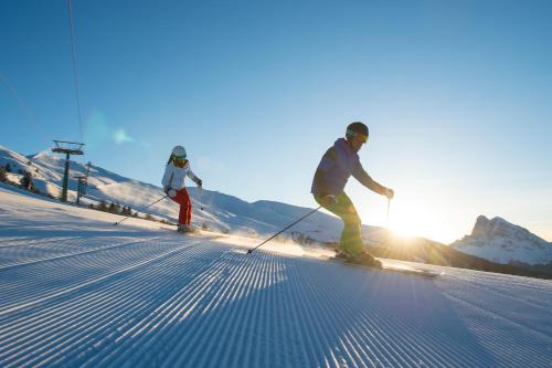 two people are skiing down a snow covered slope at Berghotel Schlemmer in Bressanone