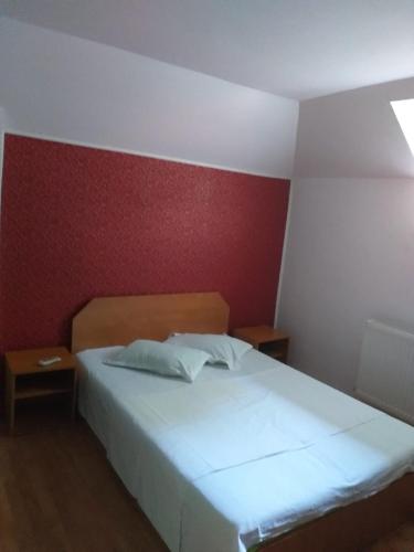 a bedroom with a white bed and a red wall at Vila Ana Lăcrămioara Concept in Căciulata