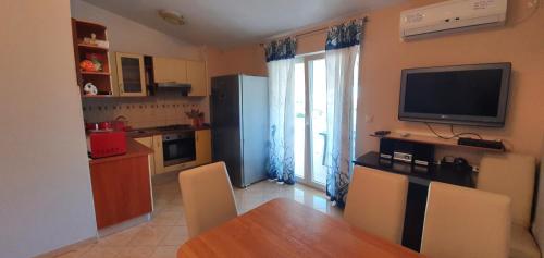 a kitchen with a dining room table and a television at Apartmani Barbara in Vinjerac