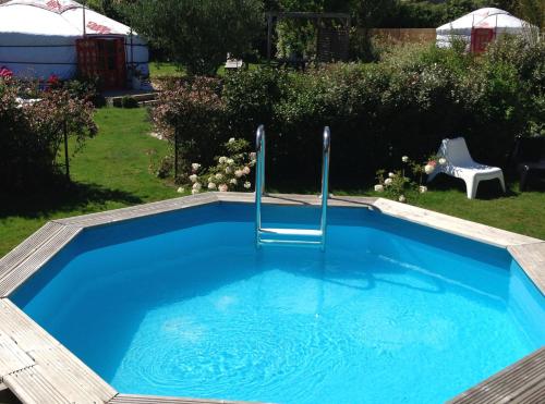 una piscina con una silla en un patio en Yourte au Paradis, en Souvigné