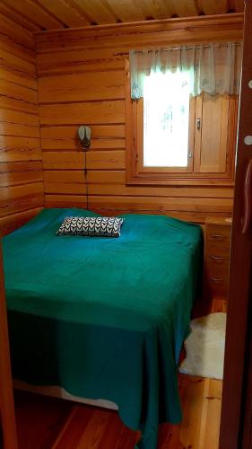 a room with a green bed in a cabin at Kotalahden mökki in Kotalahti