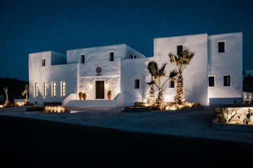 a white house with palm trees in front of it at night at Koukoumi Vegan Boutique Hotel in Ano Mera