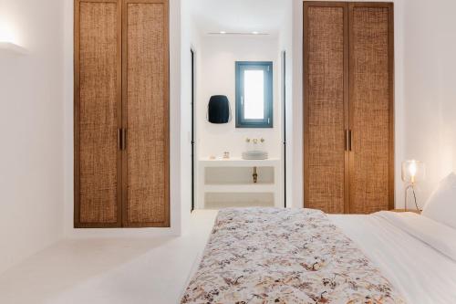 a white bedroom with a bed and a sink at Koukoumi Vegan Boutique Hotel in Ano Mera
