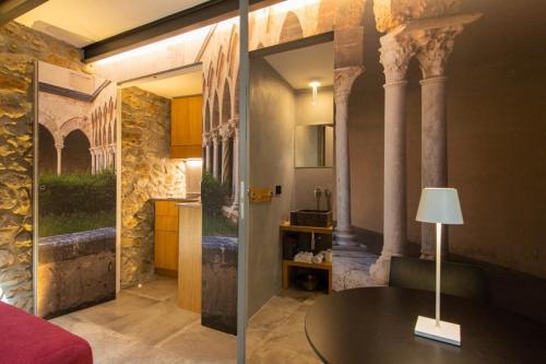 a room with a table and a kitchen with columns at MORAMUSA Charme Apartment in Cefalù