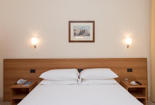 a bedroom with a white bed with two night stands at Hotel Casa Del Pellegrino in Padova