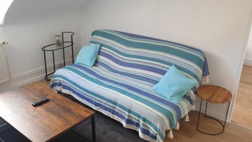 łóżko z paskowym kocem i drewnianym stołem w obiekcie Bel appartement F2 centre ville w Hawrze