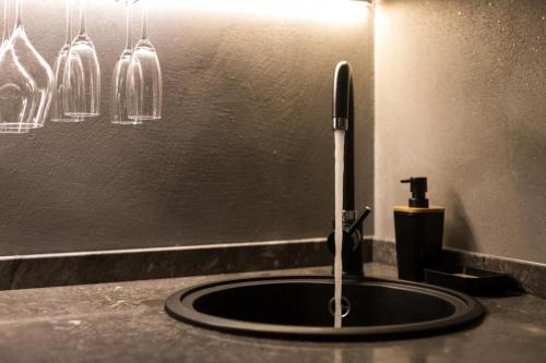 a sink with a faucet on a counter with glasses at MORAMUSA Charme Apartment in Cefalù