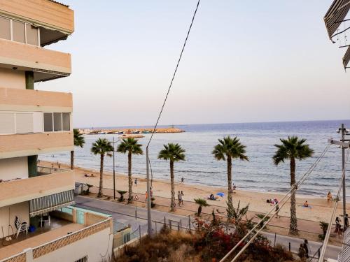 widok na plażę z palmami i budynek w obiekcie Bonefish Apartment w mieście Villajoyosa