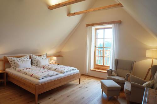 a bedroom with a bed and a chair and a window at Bauernhof Gschmeidler in Sankt Johann im Saggautal