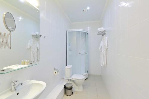 a white bathroom with a toilet and a sink at Voyage Hotels Mezonin in Stavropol