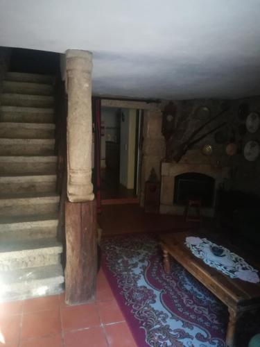a living room with a staircase and a fireplace at Casa do Campanário in Sortelha