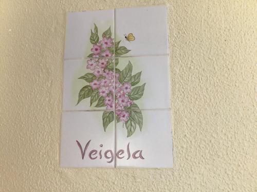 a sign on a wall with a flower and a bee at Bungalows Do Amparo in Ponta do Pargo