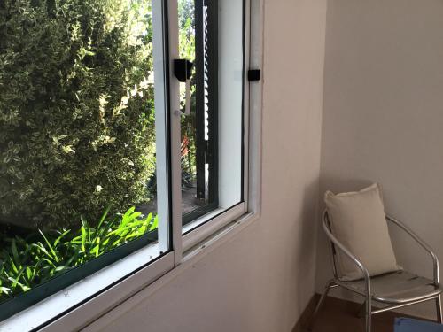 a chair next to a window with a plant at Bungalows Do Amparo in Ponta do Pargo