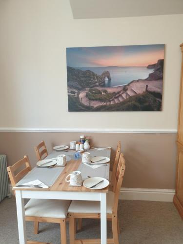 a white table with chairs and a painting on the wall at Crofton Guest House in Weymouth