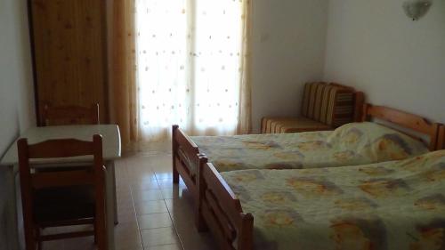 1 dormitorio con 2 camas, silla y ventana en Mouroukis Rooms, en Loutra Edipsou