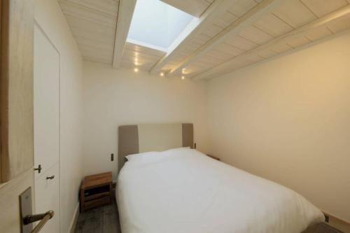 a bedroom with a white bed and a skylight at 3 pièces de grand standing aux pieds des pistes Valberg in Valberg