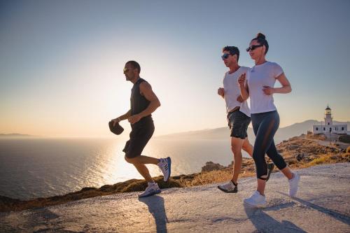 three people running on a hill near the ocean at Koukoumi Vegan Boutique Hotel in Ano Mera