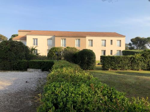a large building with bushes in front of it at Logis Hôtel Restaurant Les Aubuns in Caissargues