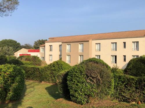 a building with bushes in front of a building at Logis Hôtel Restaurant Les Aubuns in Caissargues