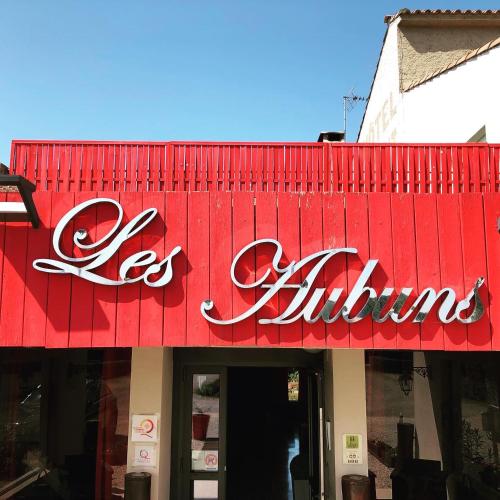 a red sign on the front of a store at Logis Hôtel Restaurant Les Aubuns in Caissargues
