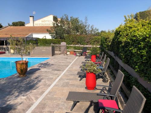 a row of chairs sitting next to a swimming pool at Logis Hôtel Restaurant Les Aubuns in Caissargues