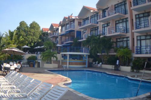 a swimming pool in front of a hotel with white chairs at Cap Lamandou Hotel in Jacmel