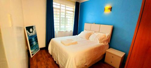 - une chambre dotée d'un lit avec un mur bleu dans l'établissement Tranquille Homestay near JKIA Airport & SGR Station Nairobi, à Nairobi