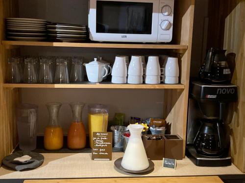 a kitchen shelf with a coffee maker and a microwave at Logis Hôtel Restaurant Les Aubuns in Caissargues