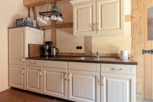 a kitchen with white cabinets and a sink and a refrigerator at Ferienhaus zur Rossfurt Tangermünde in Tangermünde