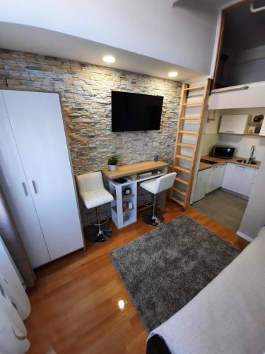 sala de estar con escritorio y pared de piedra en Studio apartman Chiara, en Zagreb