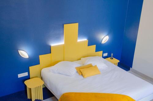 - une chambre avec un grand lit et une tête de lit jaune dans l'établissement Hôtel IMPERATOR Béziers, à Béziers