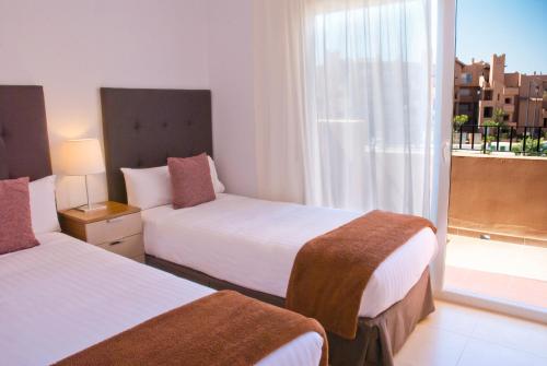 Habitación de hotel con 2 camas y ventana en The Residences At Mar Menor Golf & Resort, en Torre-Pacheco