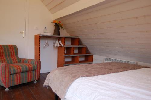 ein Schlafzimmer mit einem Bett und einem Stuhl in einem Zimmer in der Unterkunft La Vallière en Vue - gîte avec sauna in Amboise