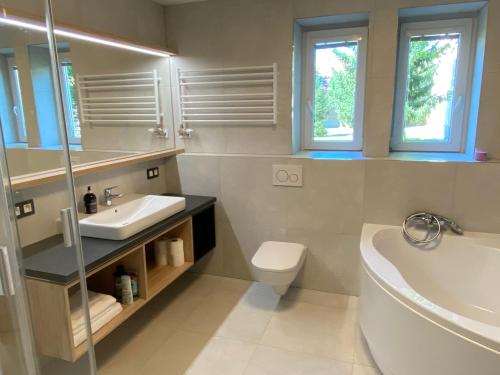 a bathroom with a sink and a tub and a toilet at Apartman Relax in Zvolen