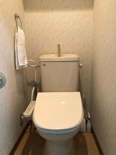 a white toilet in a bathroom with a remote control at 駅南うちやまビルさん in Fukuoka