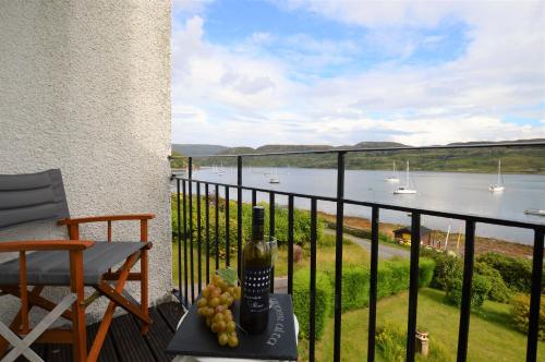 a balcony with a bottle of wine and grapes on a table at Upper Alta Apartment in Tighnabruaich