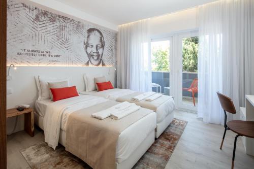 two beds in a white room with a large window at The ICONS Lisbon Central Hotel in Lisbon