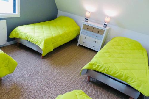 1 dormitorio con 2 camas y vestidor con sábanas amarillas en Maison avec SPA côte de granit rose, en Trégastel