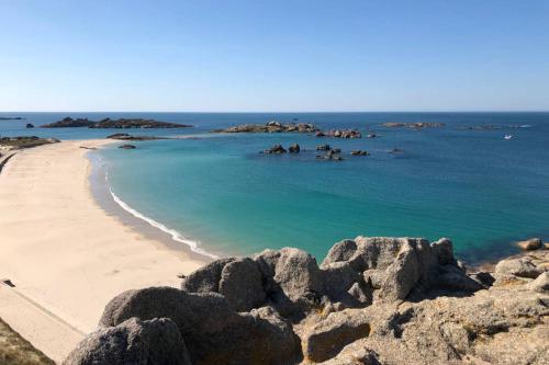 a view of a beach with rocks and the ocean at Maison avec SPA côte de granit rose in Trégastel