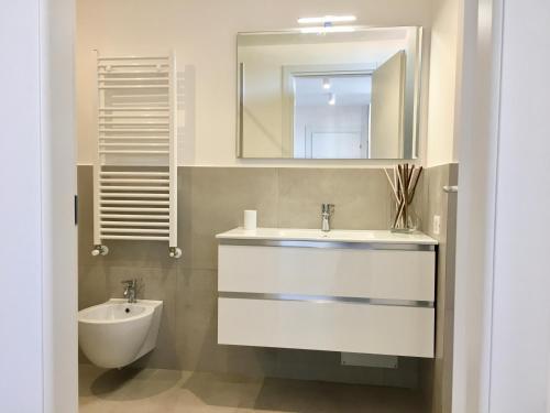 La salle de bains blanche est pourvue d'un lavabo et d'un miroir. dans l'établissement YOUR HOME MILANO Bellinzago Lombardo, à Bellinzago Lombardo