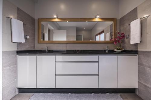 baño con armarios blancos y espejo en Vivenda da Natureza, en Santa Cruz