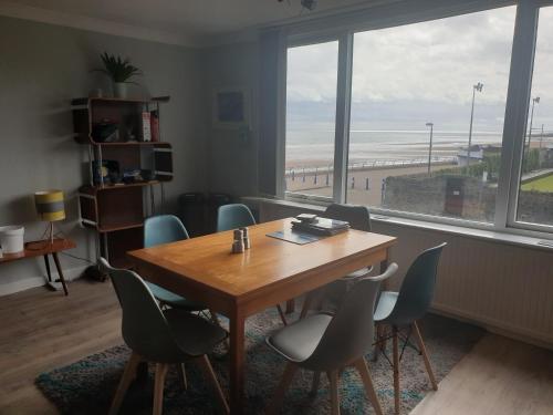 a table and chairs in a room with a view of the beach at Eastwatch guesthouse in Berwick-Upon-Tweed
